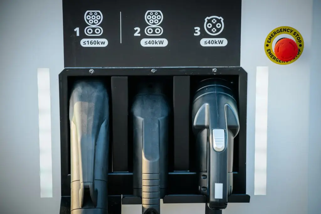 Electric vehicle charging station with three types of charging cables and an emergency stop button.
