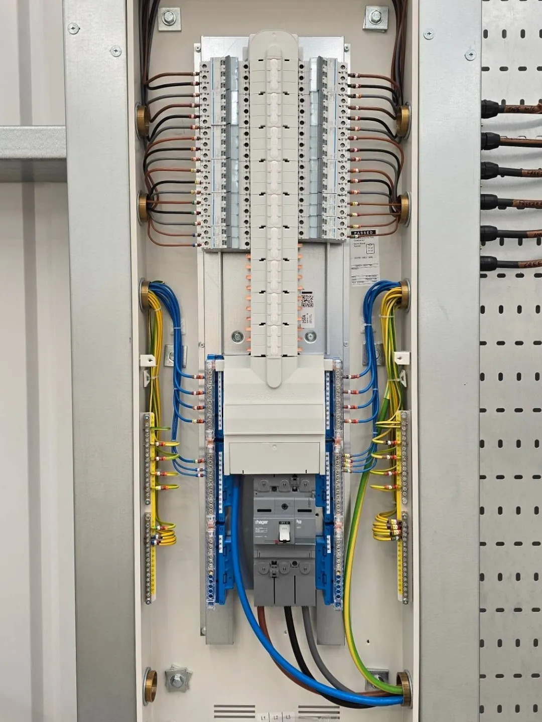 An open electrical distribution board featuring a main circuit breaker at the bottom, rows of circuit breakers above, and organized wiring connected to terminal blocks.